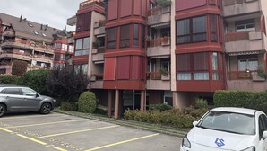 A multi-story residential building with balconies, a parking lot, and a hedge. - Large Studio Near Epfl And Lausanne City Center (Ecublens)