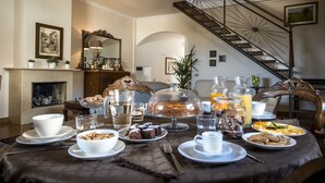 A dining table set with various breakfast items, a fireplace, and a staircase. - Residence Torremuzza - Charming House In The Heart Of Palermo with lovely view (Palermo)