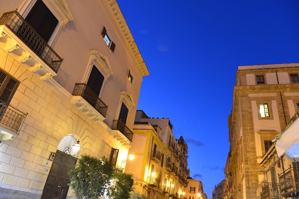 A street view at twilight with buildings featuring balconies and a street lamp.