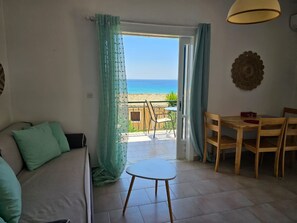Enjoy a sea view from this room, featuring a sofa, dining table, and small table with a decorative accent.