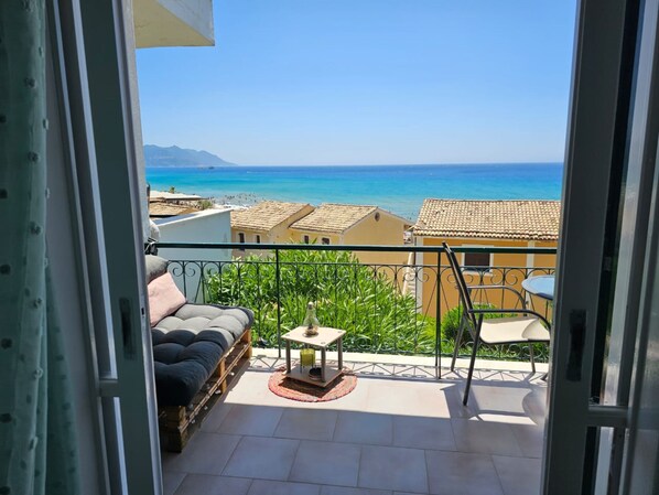 Enjoy the stunning coastal view from this balcony with a seating area, table, and chair.