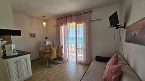 Un espacio habitable compacto con kitchenette, comedor y sofá.