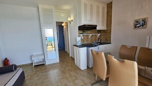 Una cocina compacta con armarios blancos, cafetera y vistas a un balcón.