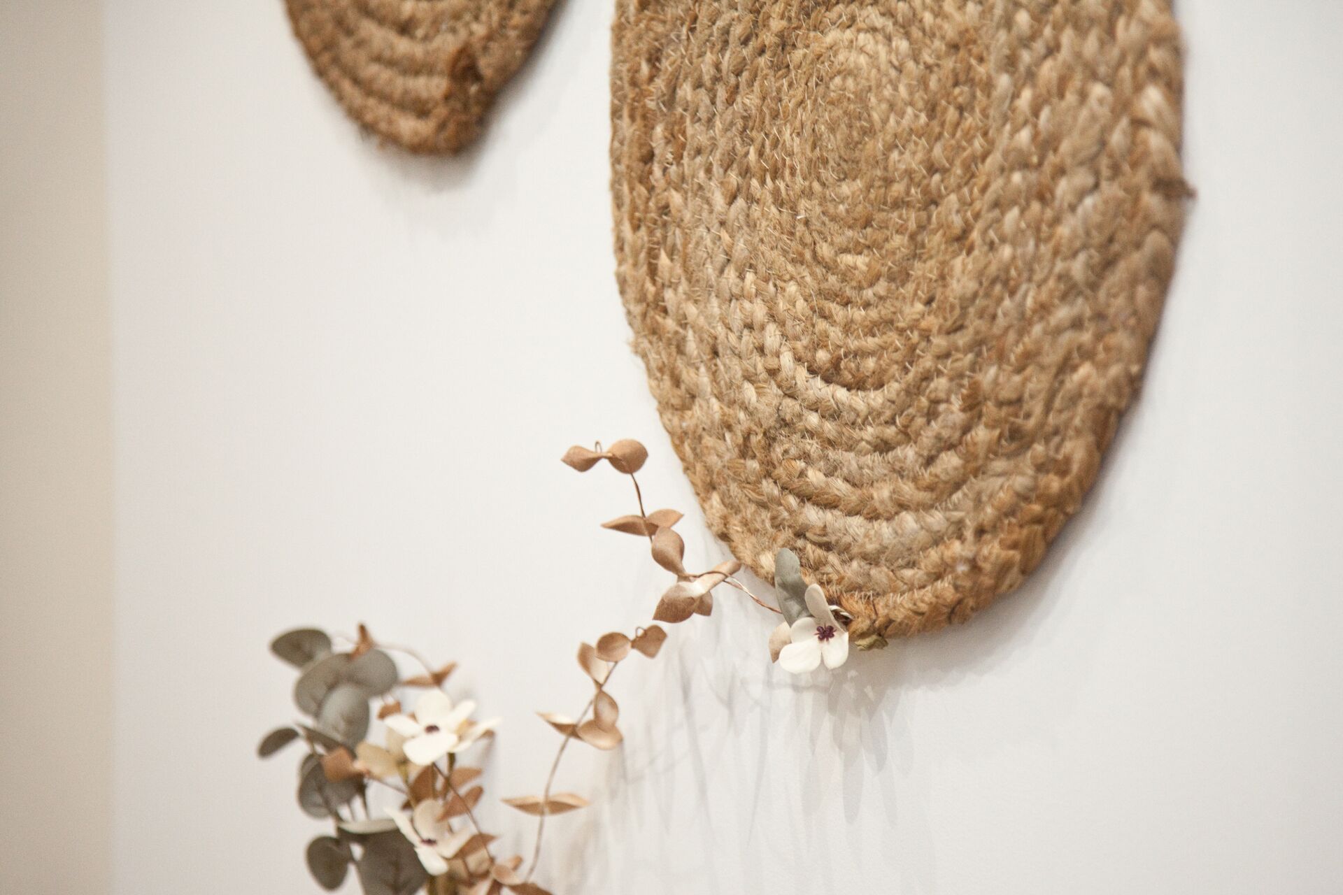 Une décoration murale texturée agrémentée d’une composition végétale.