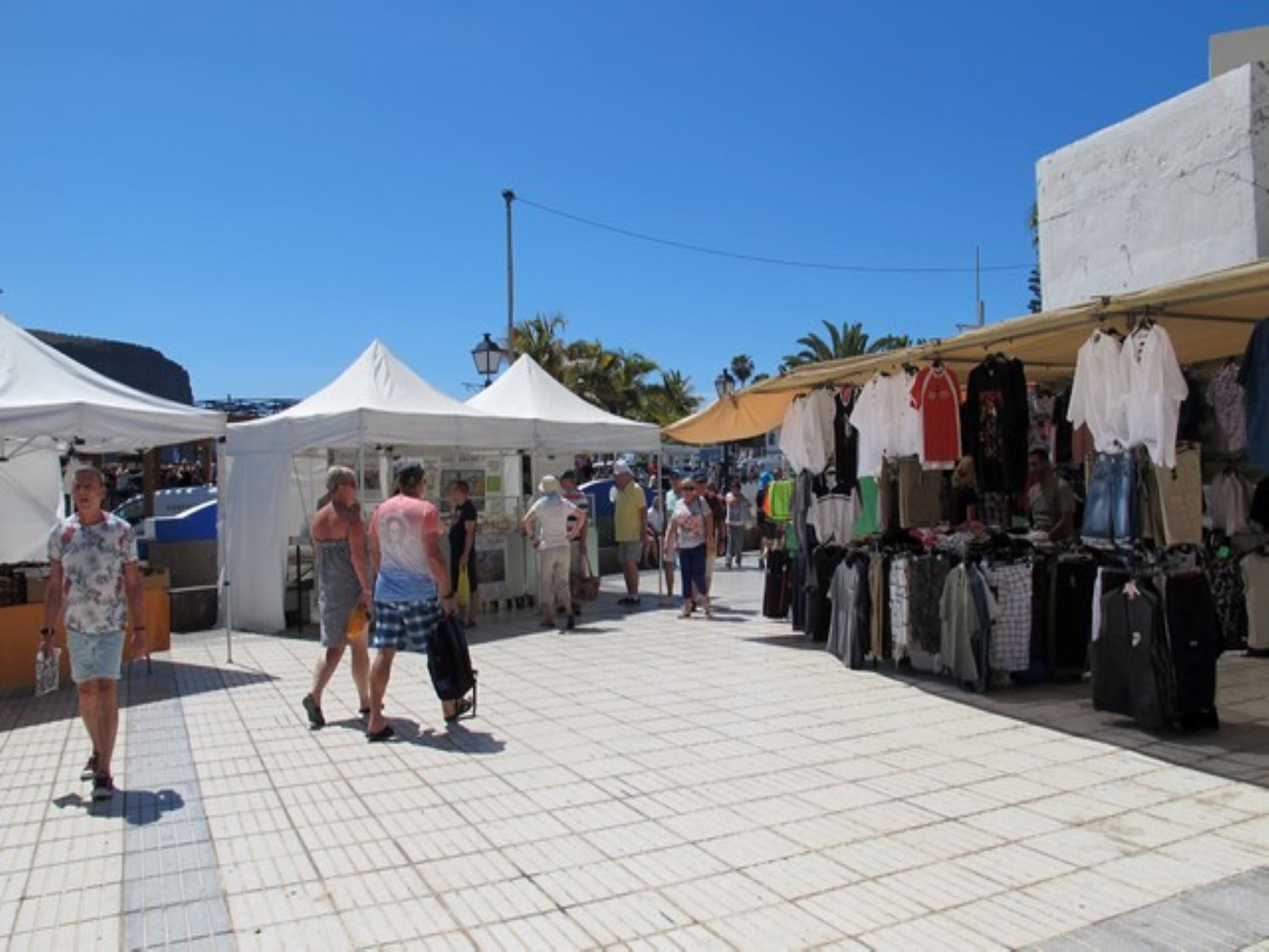 An outdoor market with tents and stalls selling clothes.