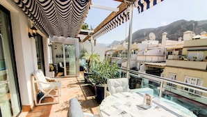 A balcony with a white table, chairs, and a striped awning. - Playa Azul , Luxury Penthouse with spectacular roof terrace (Lomo Quiebre)