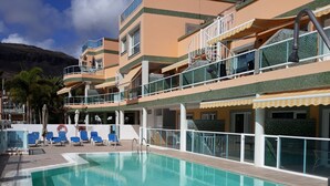 A swimming pool with a clear blue water, surrounded by lounge chairs and a building with multiple balconies. - Golden Beach n 12, top floor apartment with private roof terrace by El Sirocco (Lomo Quiebre)