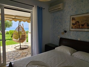 A bedroom with a bed, a hanging chair, and a view of the sea.