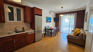 Una cocina compacta con armarios de madera, un refrigerador empotrado y una zona de comedor con mesa y sillas.