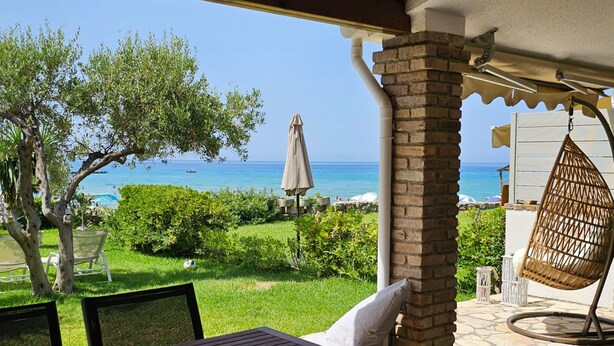 Un patio con una mesa y sillas, una hamaca colgante, y vistas al mar.