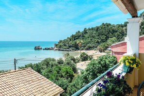 A coastal view with a balcony, a tiled roof, and a mountain backdrop.