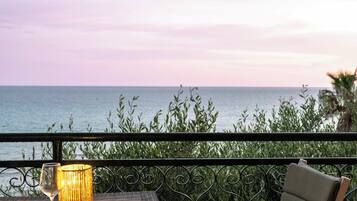 A balcony with a table, a chair, and a view of the sea.