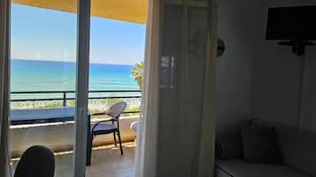 Un balcón con vistas al mar, una silla y un sofá.