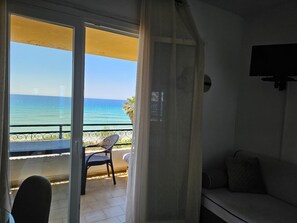 A balcony with a view of the sea, a chair, and a sofa.