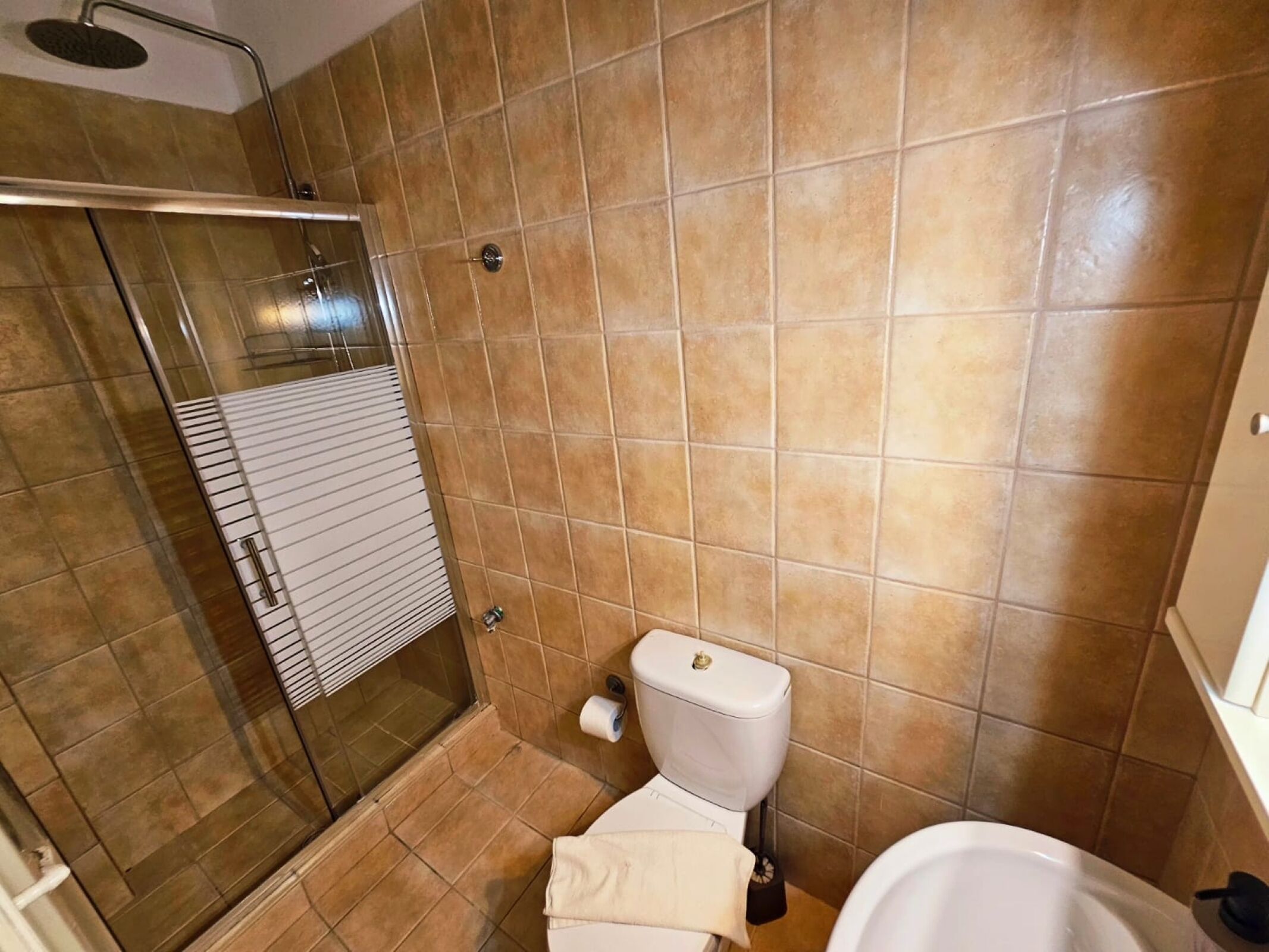 Ein Badezimmer mit Dusche, Toilette und Waschbecken.