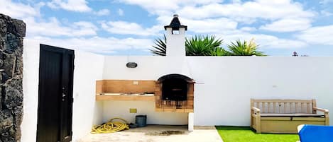 A patio with a brick oven, a wooden bench, and a stone wall.