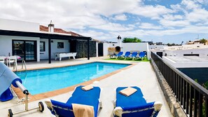 Area piscina sul tetto con poltrone da relax blu, tavolo da calcio e vista panoramica sul paesaggio circostante.