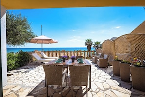 An outdoor patio with stone flooring, wicker furniture, and a view of the sea.