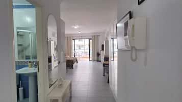 Een hotelgangen met een badkamer aan de linkerkant, een eethoek in het midden en een telefoon aan de rechtermuur.