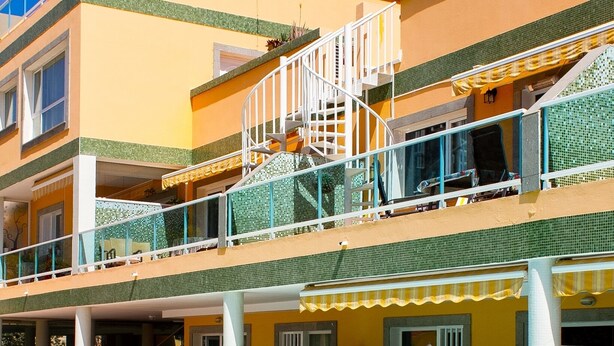 Um hotel de vários andares com piscina no andar térreo.