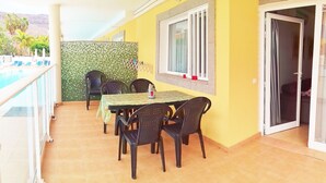 Uma área de pátio com mesa e cadeiras, piscina e vista para as montanhas.