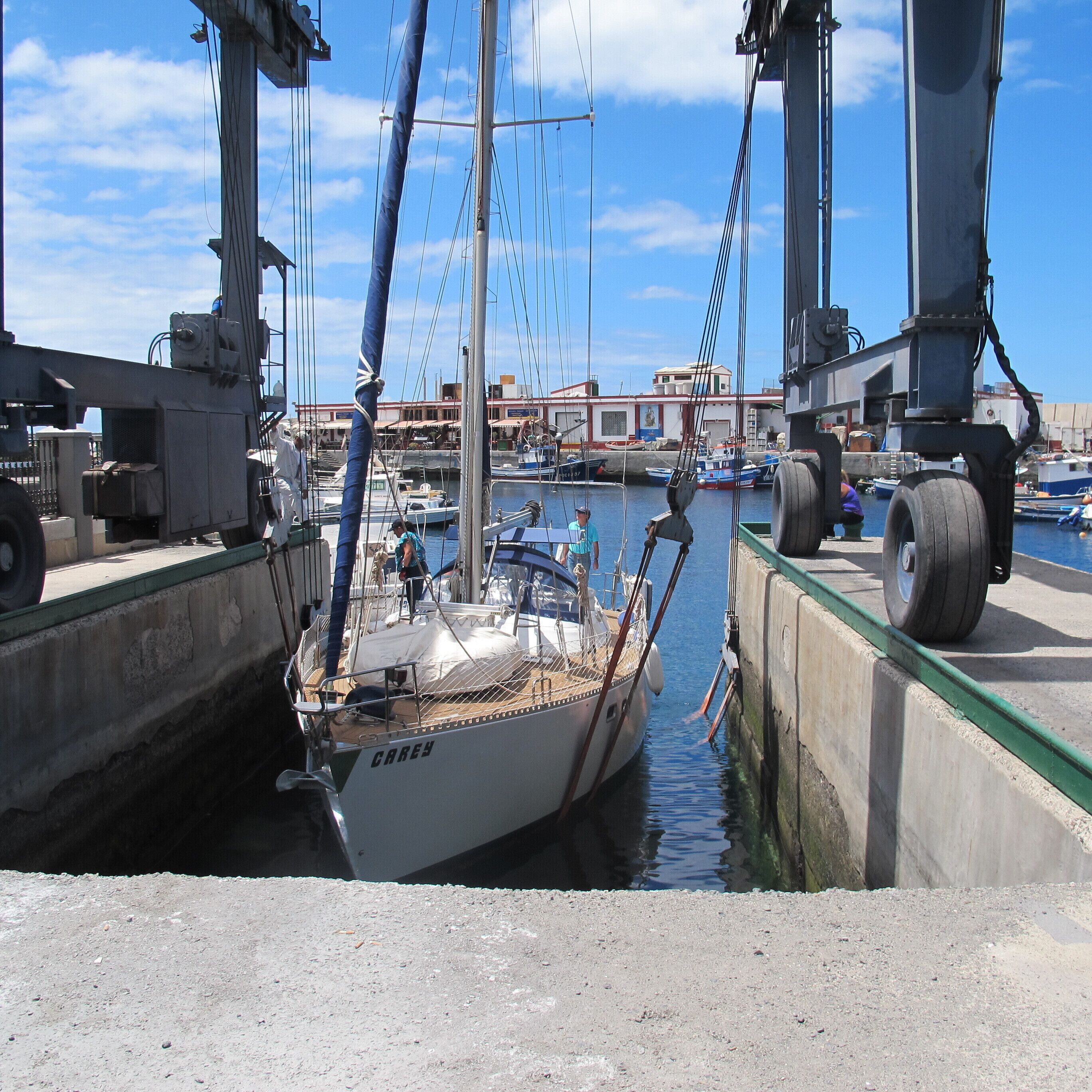 A marina with boats docked, a crane, and a building in the background.