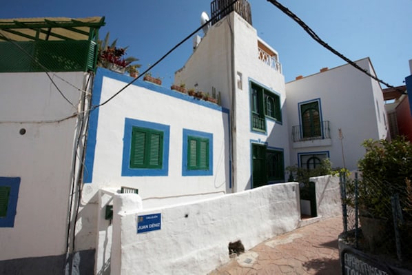 Traditional Mediterranean-style building with a flat roof and balcony overlooking a charming garden.