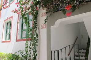 Un edificio con marcos de ventana verdes, fachada blanca y una escalera con barandilla de metal.