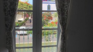 Une pièce dotée d’une porte-fenêtre coulissante donnant sur un balcon. La pièce est carrelée et comprend une petite table.