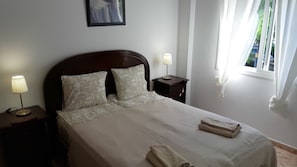 Un lit bien fait, avec des oreillers, une lampe de chevet et une table de nuit.