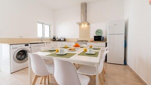Eine moderne Küche mit Essbereich, inklusive Waschmaschine, Mikrowelle und Kühlschrank.