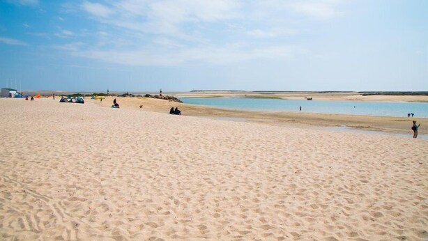 Ein weiter Sandstrand bei strahlend blauem Himmel.