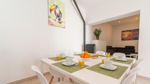 Ein Essbereich mit einem weißen Tisch, gedeckt für vier Personen, einschließlich Teller, Tassen und Gläser mit Orangensaft.