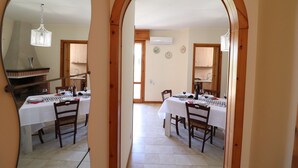 A dining area with a table set for two, a chandelier, and a view through an archway to another room. - In Good Location And With Balcony - Casa Vacanze Nicole In Salento (Otranto)