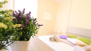 A neatly made bed with rolled towels and a potted plant with green and purple flowers. - In Good Location And With Balcony - Casa Vacanze Nicole In Salento (Otranto)