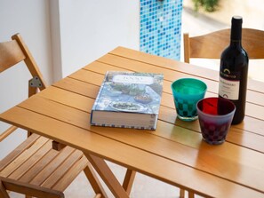 Une table en bois, sur laquelle se trouvent un livre, une bouteille de vin et deux verres.