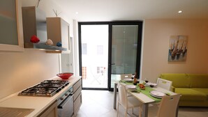 Een moderne keuken met een gasfornuis, witte kasten en een eethoek met een tafel voor twee personen.