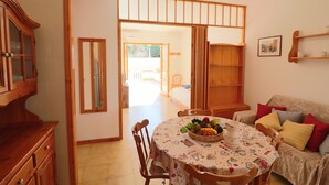 A dining area with a table set for two, a wooden cabinet, and a sofa with cushions. - Nice House Cecilia in Otranto (Otranto)