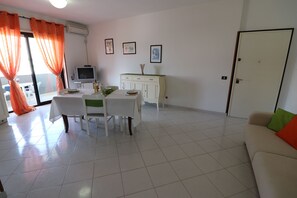 A dining area with a table, chairs, and a television on a cabinet.