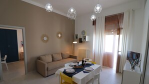 Un coin repas avec une table dressée pour quatre personnes, un canapé et un téléviseur posé sur un meuble.