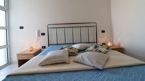 A bed with a quilt, pillows, and a bedside table with a lamp. - Casa Vanessa – Modern one-bedroom apartment with sea view in central Otranto (Otranto)
