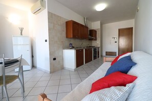 A compact living space with a kitchenette, a dining area, and a sofa with patterned cushions.