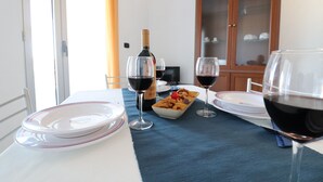 A dining table with plates, glasses, and a bottle of wine. - Casa Vanessa – Modern one-bedroom apartment with sea view in central Otranto (Otranto)