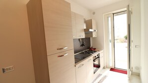 Une cuisine moderne avec des meubles en bois, une cuisinière à gaz et un tapis rouge à l’entrée.