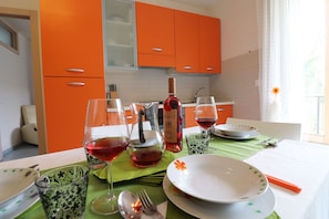Une table à manger dressée avec des assiettes, des verres et des couverts, dans une cuisine aux armoires orange.