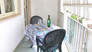 A balcony with a table set for two, featuring a patterned tablecloth and a bottle of wine. - Holiday Apartment Karm Otranto 6 places (Otranto)
