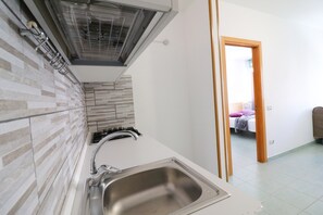 A kitchen with a stainless steel sink, a modern faucet, and a tiled backsplash. - Bilo Nadia — Cozy Apartment 200 m from Otranto’s Castle (Otranto)