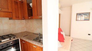 A kitchen with wooden cabinets, a gas stove, and a sink. - Casa vacanze "clio" centro Otranto, Salento 6 posti (Otranto)