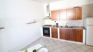 A kitchen with wooden cabinets, a stove, oven, and a refrigerator.