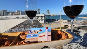 Een tafel met twee glazen rode wijn, een brochure en een bord gebak.